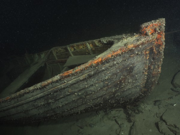 Wreck of a rowing boat lies on the sandy lake bottom in the dark water, dive site Schoggiwand, Lake Zurich, Kilchberg, Zurich, Switzerland