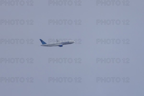 Jet passenger aircraft of United Airlines flying in a blue sky, England, United Kingdom