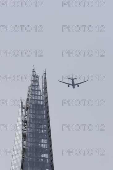 Jet passenger aircraft in flight over The Shard skyscraper building, London, England, United Kingdom