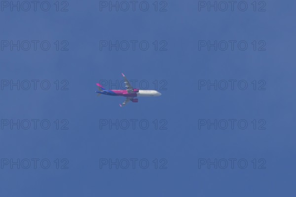 Airbus A321 jet aircraft of Wizz Air airlines in flight in a blue sky, England, United Kingdom