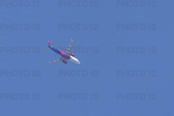 Airbus A321 jet aircraft of Wizz Air airlines in flight in a blue sky, England, United Kingdom