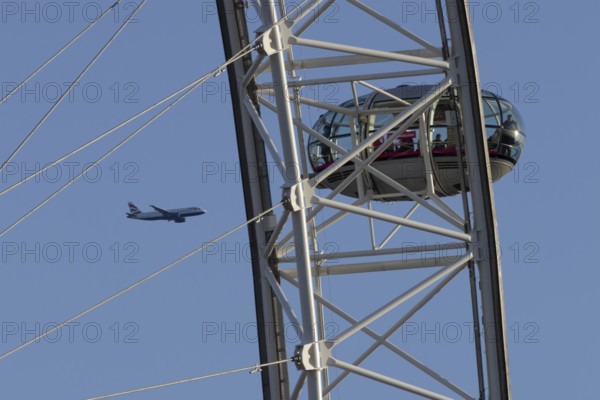 Airbus A320-232 jet passenger aircraft of British Airways airlines in flight in a blue sky with the London Eye wheel in the foreground, London, England, United Kingdom