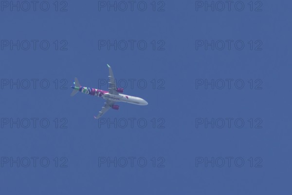 Airbus A321 jet aircraft of Wizz Air airlines in flight in a blue sky, England, United Kingdom
