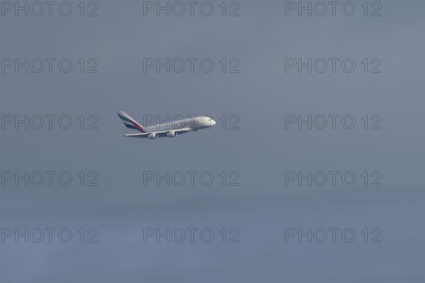 Airbus A380 jet passenger aircraft of Emirates airlines flying in a blue sky, England, United Kingdom