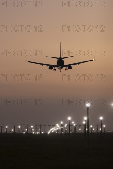 Boeing 737 jet passenger aircraft of Ryanair airlines landing over runway lights at sunset, London Stansted airport, Essex, England, United Kingdom