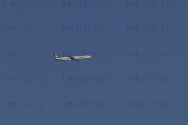 Boeing 777 jet passenger aircraft of Singapore airlines in flight in a blue sky, England, United Kingdom