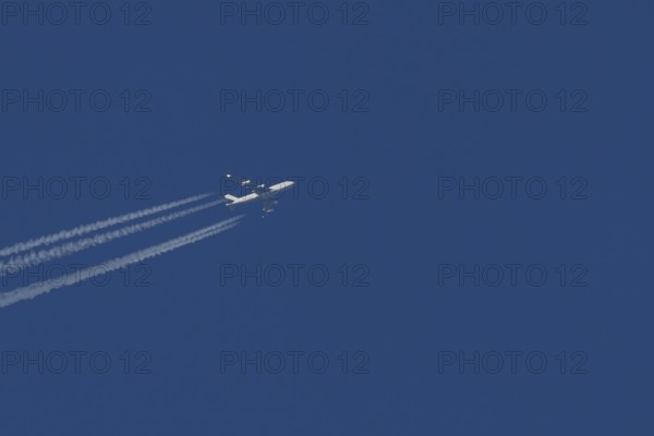 Boeing 747 Jumbo jet cargo aircraft in flight in a blue sky with vapour trails or contrails behind, England, United Kingdom