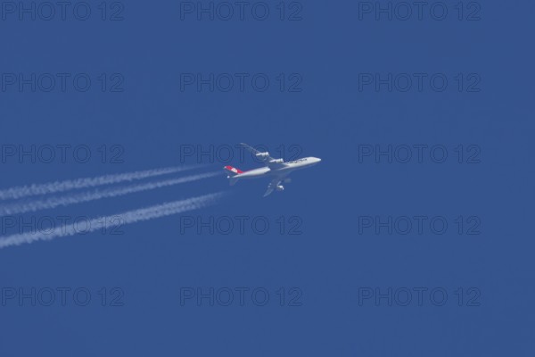 Boeing 747 Jumbo jet cargo aircraft of Cargolux airlines in flight in a blue sky with vapour trails or contrails behind, England, United Kingdom