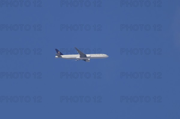 Boeing 777 jet passenger aircraft of Saudi airlines in flight in a blue sky, England, United Kingdom