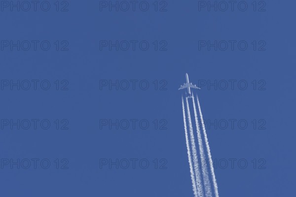 Airbus A340-300 jet aircraft of Lufthansa airlines in flight in a blue sky with vapour trails or contrails behind, England, United Kingdom