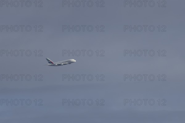 Airbus A380 jet passenger aircraft of Emirates airlines flying in a blue sky, England, United Kingdom