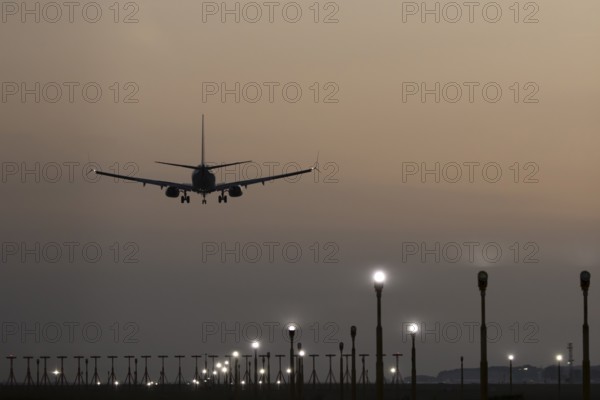 Boeing 737 jet passenger aircraft of Ryanair airlines landing over runway lights at sunset, London Stansted airport, Essex, England, United Kingdom