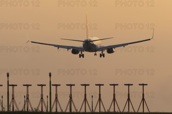 Boeing 737 jet passenger aircraft of Ryanair airlines landing over runway lights at sunset, London Stansted airport, Essex, England, United Kingdom