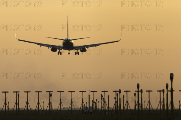 Boeing 737 jet passenger aircraft of Ryanair airlines landing over runway lights at sunset, London Stansted airport, Essex, England, United Kingdom
