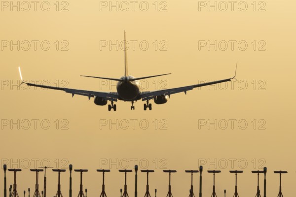 Boeing 737 jet passenger aircraft of Ryanair airlines landing over runway lights at sunset, London Stansted airport, Essex, England, United Kingdom