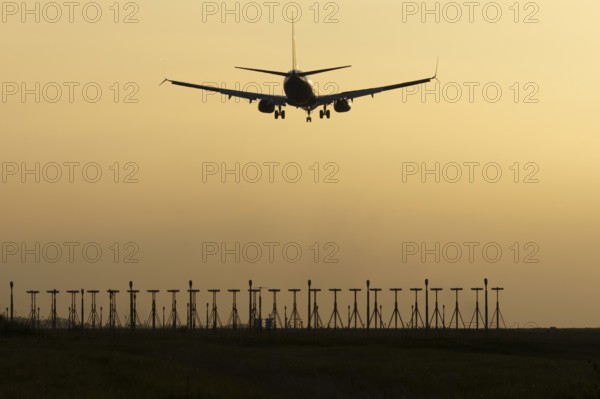 Boeing 737 jet passenger aircraft of Ryanair airlines landing over runway lights at sunset, London Stansted airport, Essex, England, United Kingdom