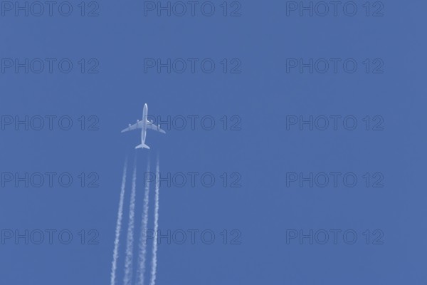 Airbus A340-300 jet aircraft of Lufthansa airlines in flight in a blue sky with vapour trails or contrails behind, England, United Kingdom
