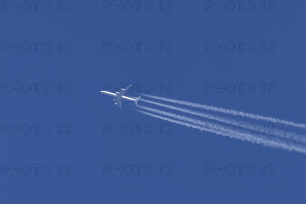 Airbus A340-300 jet aircraft of Lufthansa airlines in flight in a blue sky with vapour trails or contrails behind, England, United Kingdom