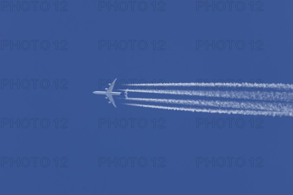 Airbus A340-300 jet aircraft of Lufthansa airlines in flight in a blue sky with vapour trails or contrails behind, England, United Kingdom