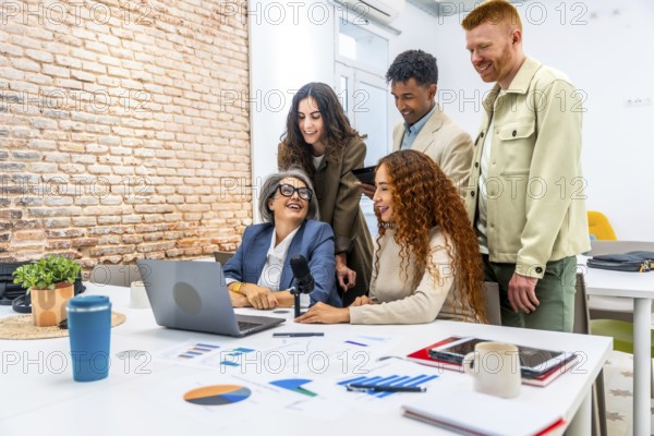 Diverse business professionals sharing ideas and laughing together during a collaborative podcast recording session or team meeting in a modern office space