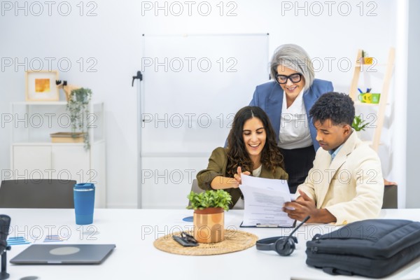 Diverse business professionals reviewing and discussing a document, demonstrating teamwork and collaboration in a bright, contemporary office setting, focusing on shared progress and smiling