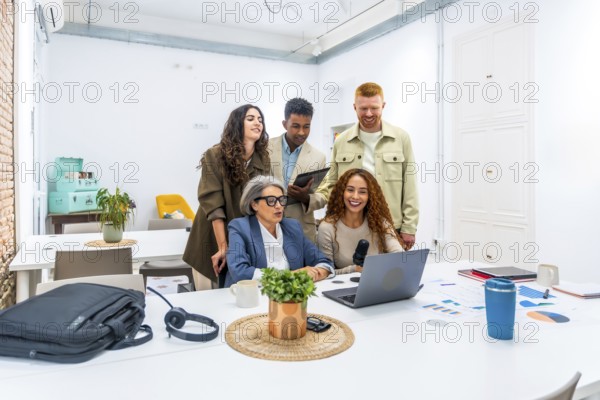 Diverse business team recording a podcast in a modern office, collaborating on content creation, brainstorming ideas, and using laptops and microphones for digital media production