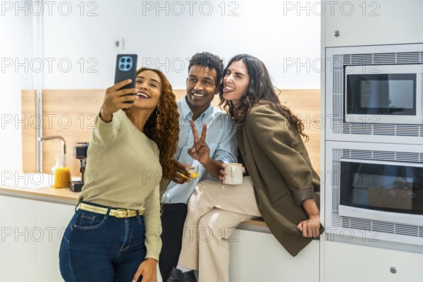 Diverse coworkers cheerfully taking a selfie on a smartphone during a relaxed office kitchen break, sharing laughs and casual bonding over coffee and snacks