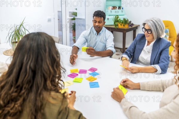 Diverse business team collaborating and exchanging ideas in a creative meeting, using colorful sticky notes on a white table during a planning session