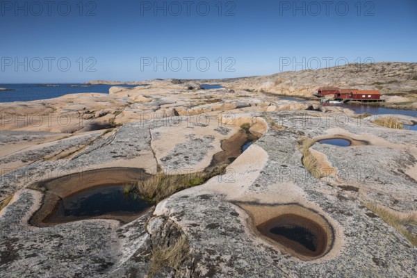 Rocks with rainwater puddles, falun red houses, rocky coast, Bohus granite, Ramsvik, nature reserve Ramsviklandet, Bohuslän, Skagerrak, Sotenäs, Västra Götalands län, Sweden
