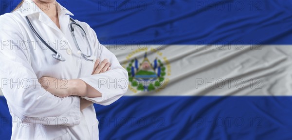 Doctor with crossed arms on El Salvador flag. El Salvador health and care concept. Female doctor on El Salvador flag