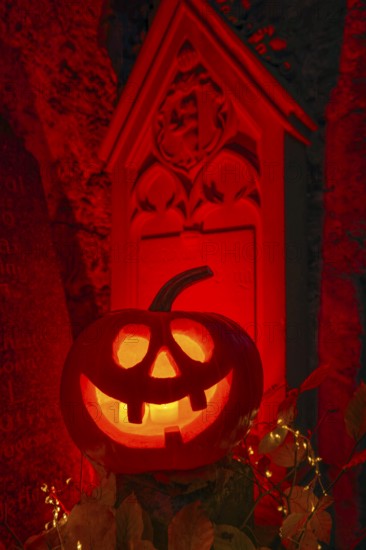 Halloween pumpkin with candlelight in the cemetery, illuminated red and spooky
