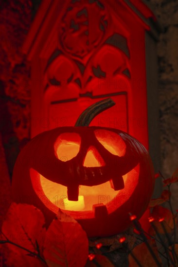 Halloween pumpkin with candlelight in the cemetery, illuminated red and spooky
