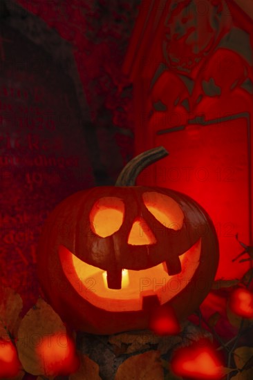 Halloween pumpkin with candlelight in the cemetery, illuminated red and spooky