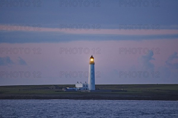 Lighthouse at dusk illuminating the sea, Orkney Islands, Scotland, Great Britain