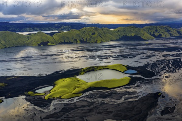 Turquoise-coloured crater lake with moss-covered crater rims in the Icelandic highlands, surrounded by glacial rivers, Iceland