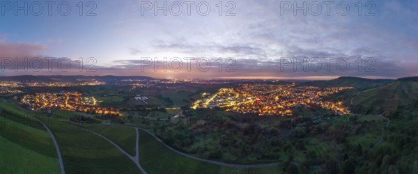 Expansive landscape with illuminated city at dusk and cloudy sky, Korb and Kleinheppach in Rems Valley, Baden-Württemberg, Germany