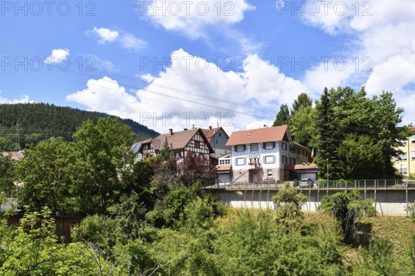 Forbach, Germany - July 12th 2025: Buildings surrounded by trees in Forbach. Scenic summer view of Black Forest town under blue sky