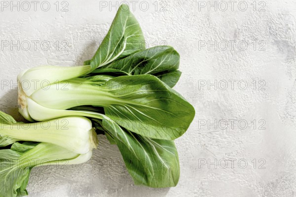 Fresh bok choy, laid out on a light gray surface, top view, natural light