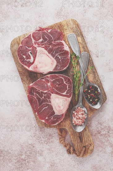 Knuckle on the bone, raw ossobuco meat, on a wooden chopping board, with spices, top view, no people