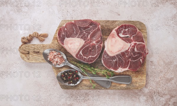Knuckle on the bone, raw ossobuco meat, on a wooden chopping board, with spices, top view, no people