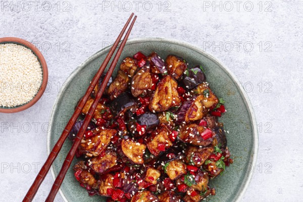 Fried eggplant, Chinese style, in sweet and sour sauce, with pepper and sesame seeds, in a green bowl