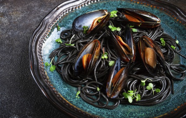 Black spaghetti, nori pasta, with mussels, top view, on a dark background, homemade, no people