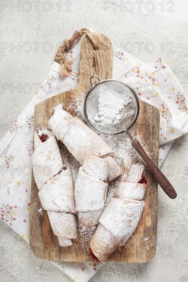 Bagels with filling, sweet pastries, sprinkled with powdered sugar, on a wooden board, dessert, breakfast