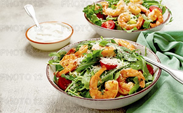 Two bowls of shrimp salad, arugula and cherry tomatoes, with parmesan cheese, healthy food