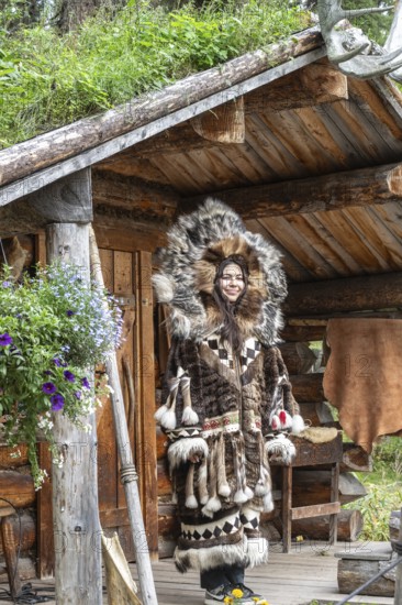Young Tlingit woman in traditional traditional costume in front of a hut, Chena Village, Alaska, USA