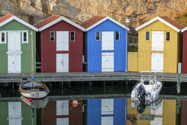 Colourful boathouses and boats in the calm water in front of rocks in the harbour of Smögen, Smögenbryggan, Västra Götalands Län, Bohuslän, Sweden