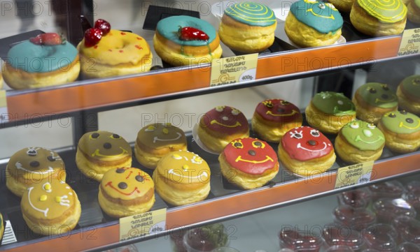 Donuts with colourful glazes and faces in a glass display, Gntunik supermarket, Aragazotn province, Armenia