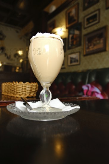 A coffee drink with whipped cream sits on a table in an English pub