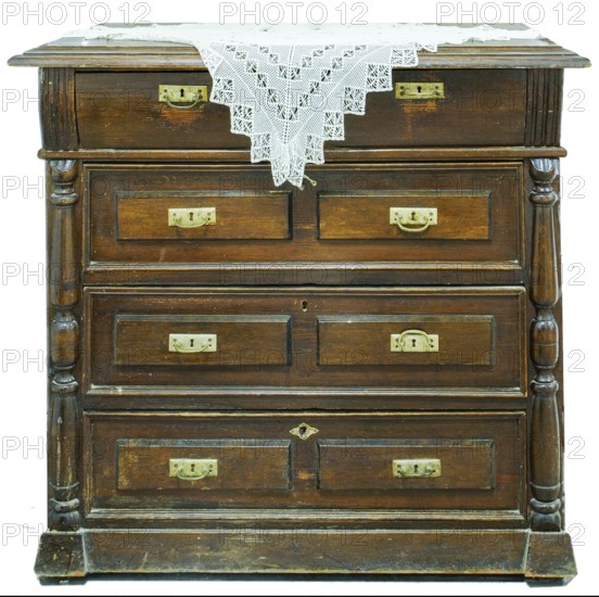 A vintage chest of drawers covered with an openwork crocheted doily