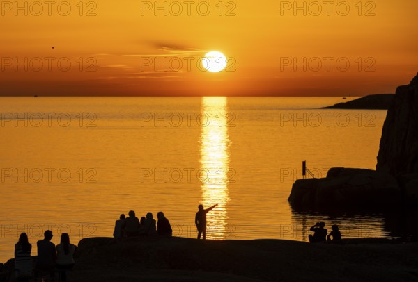 Silhouettes of tourists, sun melting in the sea, sunset, archipelago landscape, Smögen, Smögenbryggan, Västra Götalands Län, Bohuslän, Sweden